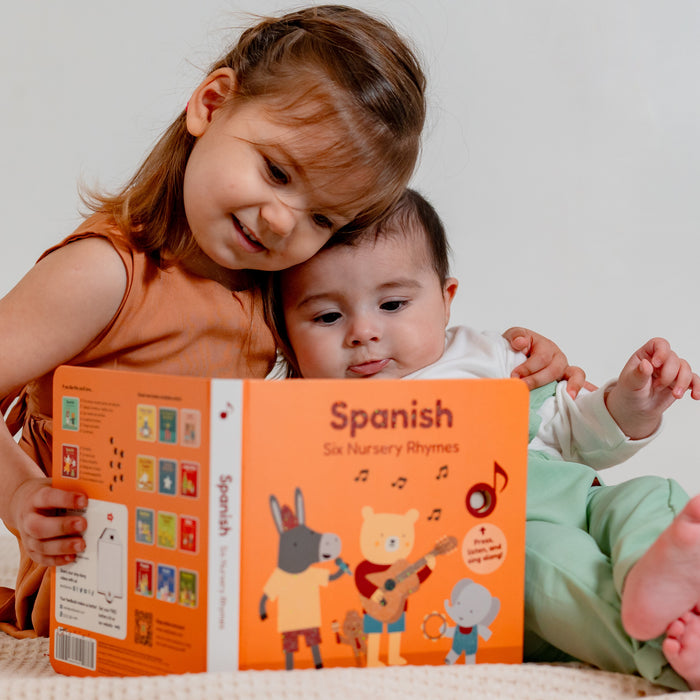 A little girl and a baby are reading a spanish book. Spanish books, bilingual books, children books, kids language, language books for kids.